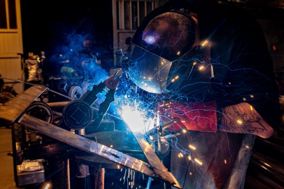 Soudage à l'arc avec étincelles et lumière intense dans un atelier.