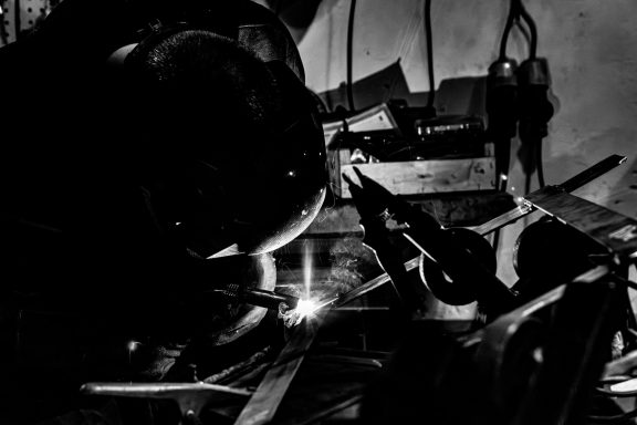 Bricolage en noir et blanc, soudure à l'arc avec des éclats lumineux sur des métaux.